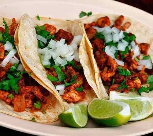 Three tacos al pastor with onion, cilantro and lime